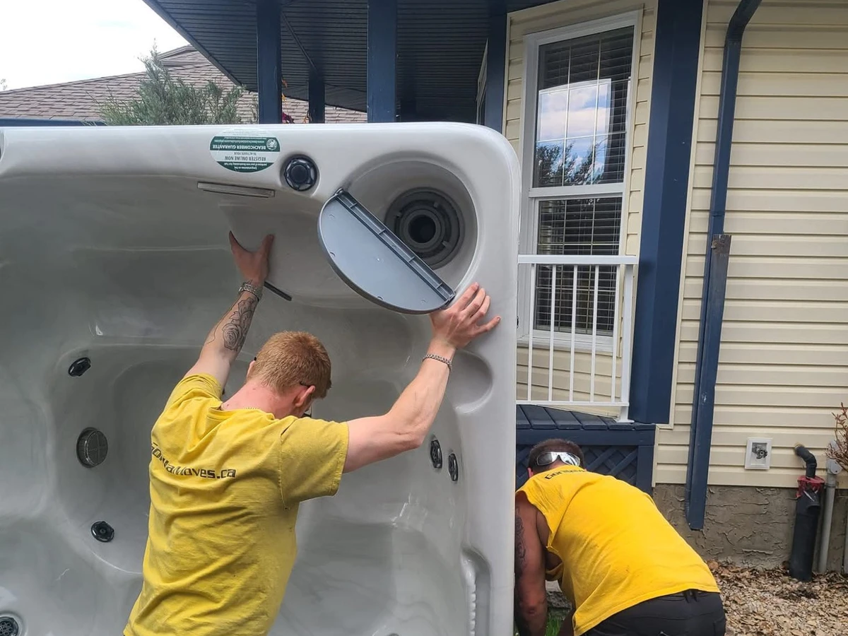 Two Gorilla Moves labour crew members in yellow shirts moving a hot tub outside a BC home