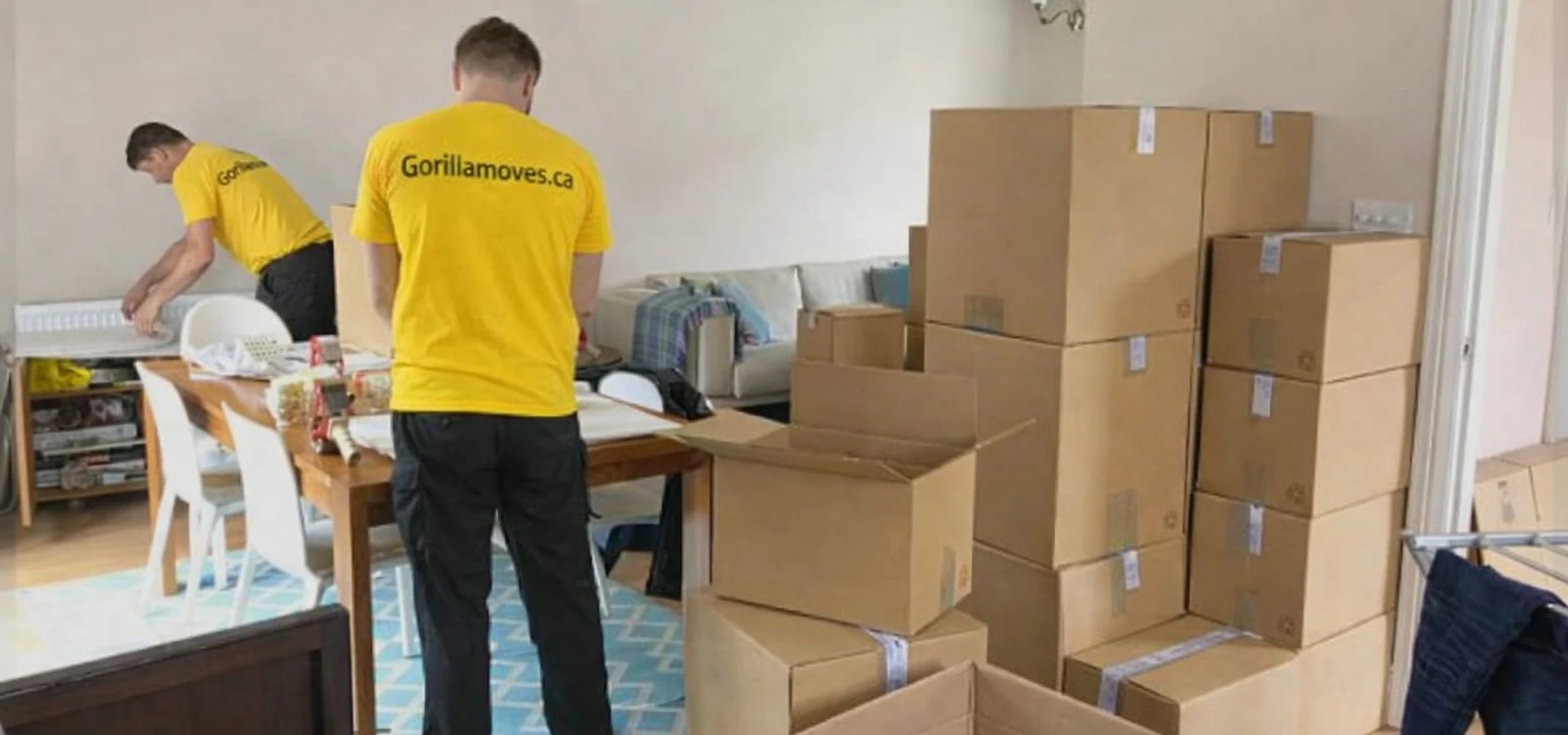 Two Gorilla Moves crew members in yellow shirts packing boxes in a Fraser Valley home